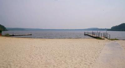 Picture or Budd Lake beach looking across the sand toward the lake with the docks on the left and right